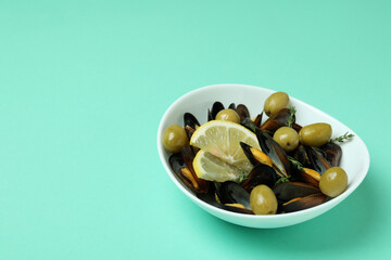 Bowl of mussels with spices on mint background
