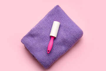 Lint roller and clothes on color background