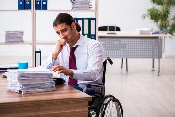 Young male employee after accident in wheel-chair at workplace