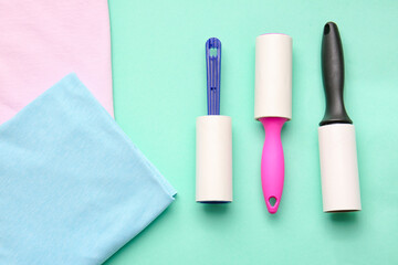 Lint rollers and clothes on color background