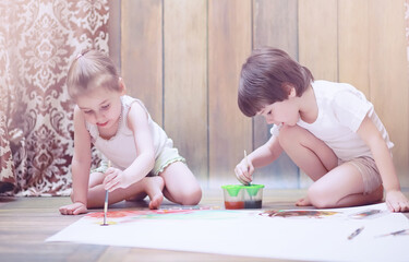 Little children paint on a large sheet of paper