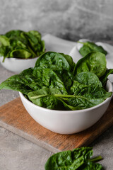 Bowl with fresh spinach leaves on grunge background