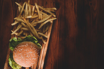 Fried potatoes and homemade burger on wooden table.
