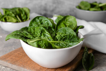 Bowl with fresh spinach leaves on grunge background, closeup
