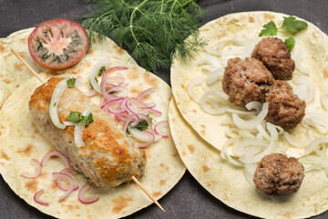 Kebab on skewer and meatballs with tomatoes and onions on pita