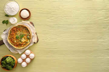Spinach tart and ingredients on color wooden background