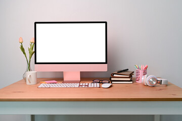 Front view computer with white screen ad supplies on wooden desk.