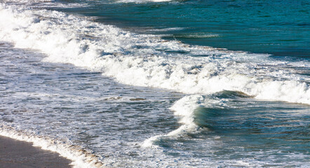 Sea waves and splashes of water on  sandy beach.