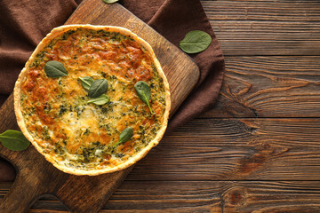 Board with tasty spinach tart on wooden background