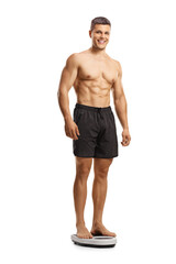 Fototapeta premium Full length shot of a shirtless young man standing on a weight scale and looking at camera