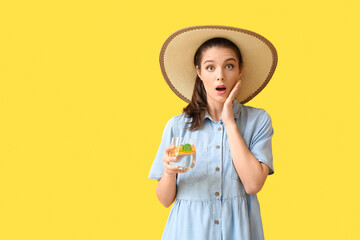 Surprised young woman with fresh lemonade on color background