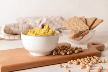 Bowl with tasty hummus, chickpeas and crackers on light background, closeup