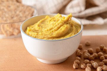 Bowl with tasty hummus and chickpeas on table, closeup