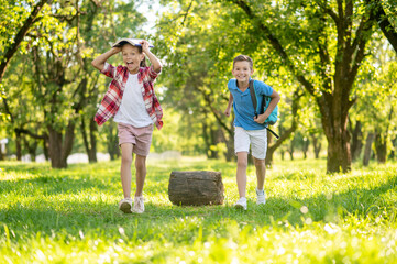 Cheerful girl and boy with backpack in park