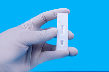Health worker hand with protective gloves holding covid-19 antigen test kit