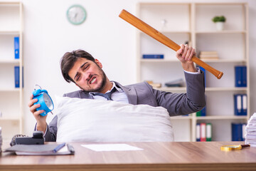 Young male employee in oversleeping concept