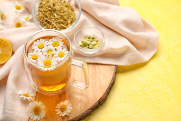 Composition with cup of chamomile tea and flowers on color background