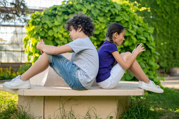 Boy and girl with smartphones in park