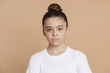 Serious teenage girl with a bundle of hair looks at the camera. Cute little girl on a pink...