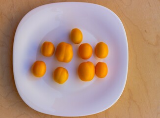 Ripe yellow cherry tomatoes on a glossy white plate. View from above
