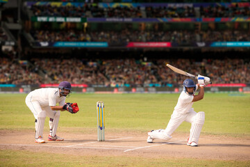 Cricketer batsman hitting a shot during a match on the pitch