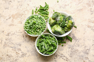 Bowls with frozen green vegetables on color background