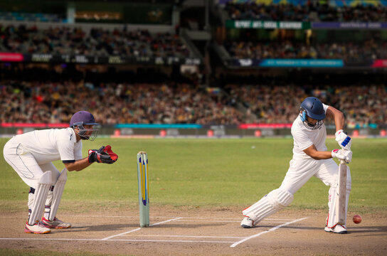 Cricketer batsman hitting a shot during a match on the pitch
