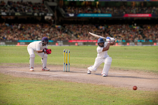Cricketer batsman hitting a shot during a match on the pitch