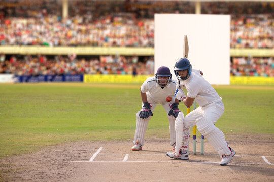 Cricketer batsman hitting a shot during a match on the pitch