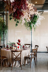 Elegant table set with glasses decorated in red with wooden chairs
