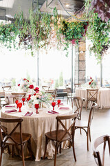 Elegant festive wedding decor with vintage wood chairs, powdery tablecloths and hanging flowers and foliage from the ceiling.
