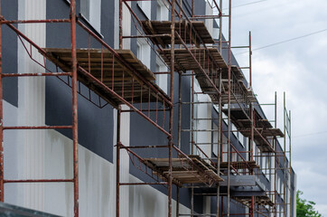 Scaffolding against Dark gray building with white windows. Beaut