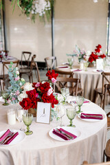 Restaurant wedding decor with red glasses and purple flowers. Vintage wooden chairs