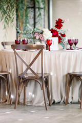 Restaurant wedding decor with red glasses and purple flowers. Vintage wooden chairs