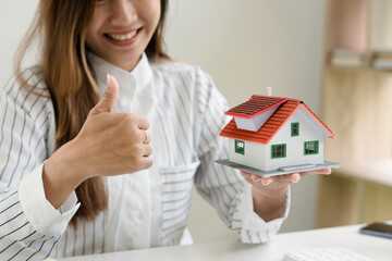 Hands of young woman holding model house, real estate insurance and banking concept.