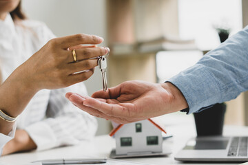 Real Estate agent with customer making contract signature giving a key buy / rent a house
