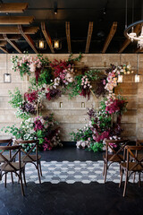 wedding arch at the restaurant with red flowers and wooden chairs