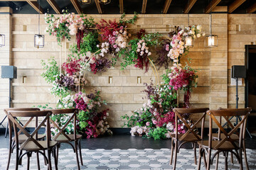 Fototapeta na wymiar wedding arch at the restaurant with red flowers and wooden chairs