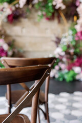 wedding arch at the restaurant with red flowers and wooden chairs