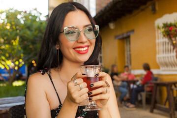 young woman smiles while drinking tea outdoors