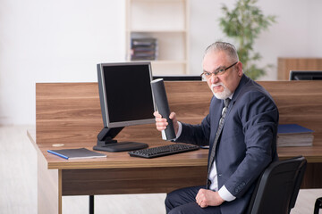 Aged male employee sitting at workplace