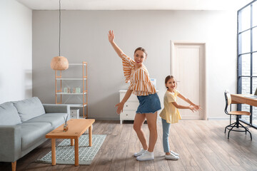 Young woman and her little daughter dancing at home