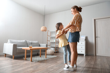 Young woman and her little daughter dancing at home