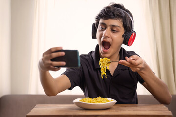 A CHEERFUL TEENAGER CLICKING SELFIE WHILE EATING MAGGI