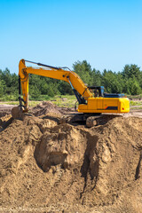 An industrial yellow excavator develops in a sandpit quarry. Industry, technology, mining. Heavy industrial machinery.