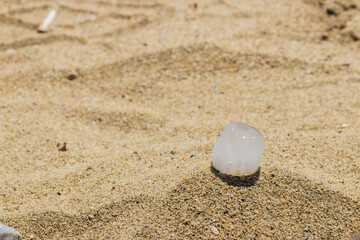 Ice cube on the sand during a sunny day