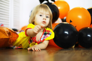 Portrait of a small child lying on the floor in a room decorated with balloons. Happy childhood concept.