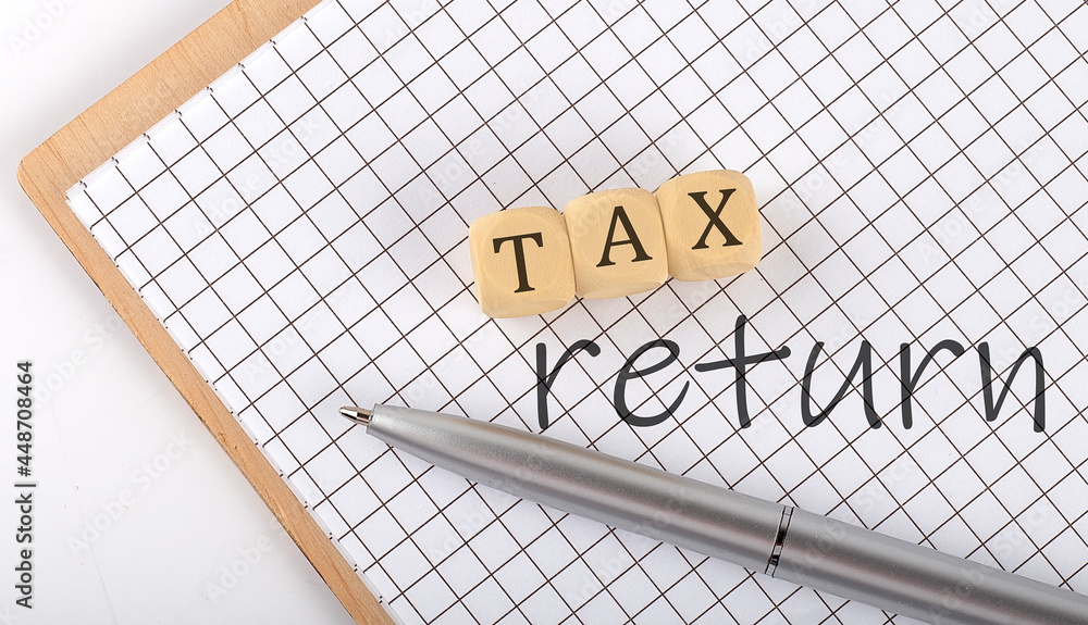 Poster tax return text concept written on the wooden cubes blocks and notebook