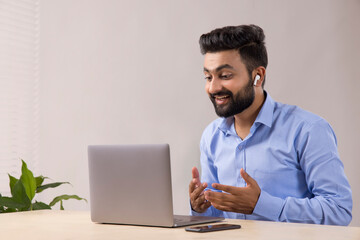 A SMART YOUNG MAN TALKING OVER VIDEO CONFERENCING IN LAPTOP