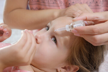 close up mother drips in eyes of the girl a medicinal solution